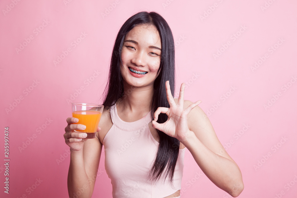 Young Asian woman drink orange juice show OK sign. Young Asian woman drink orange juice show OK sign.