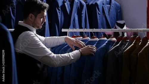 Young man choosing classical suit in the suit shop