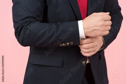 Close-up of hands adjusting white sleeve in blue suit.