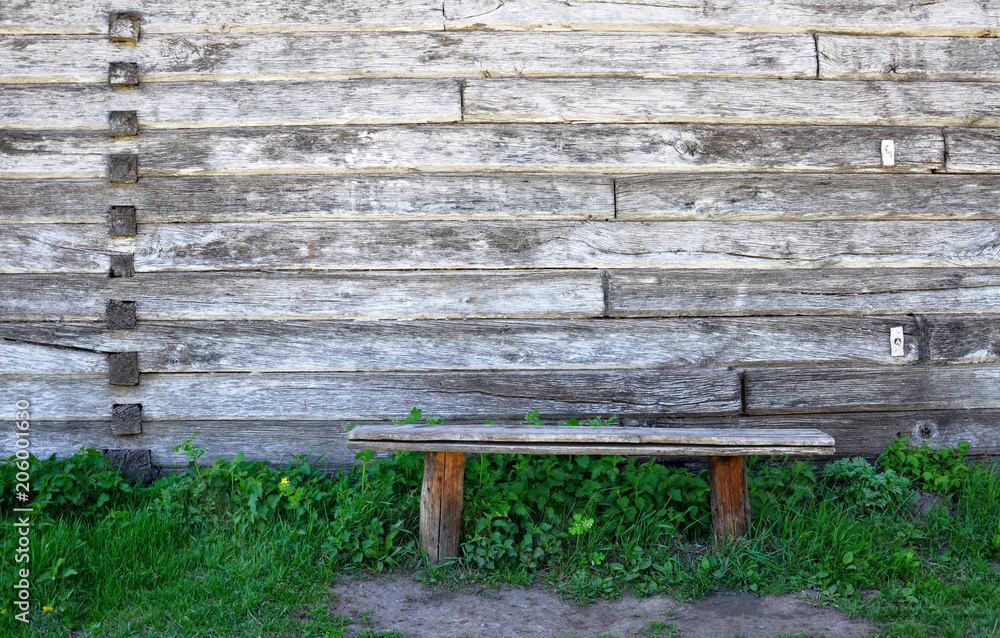 old wooden bench standing in the grass against the background of a wooden wall old wooden bench standing in the grass against the background of a wooden wall