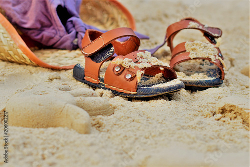 Sand on the beach or in the sandbox and footprints in the sand. Form for sand and children's shoes nearby. Nearby accessories to protect the sun rays of parents. Background image for copy space.