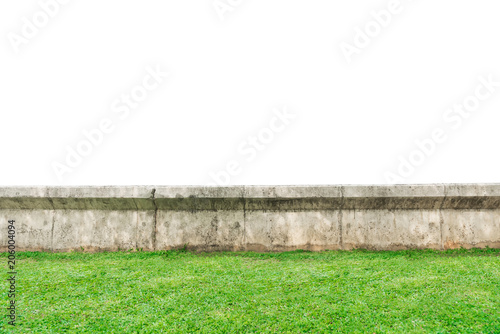 Old gray concrete fence stands on green grass, isolated on white background.