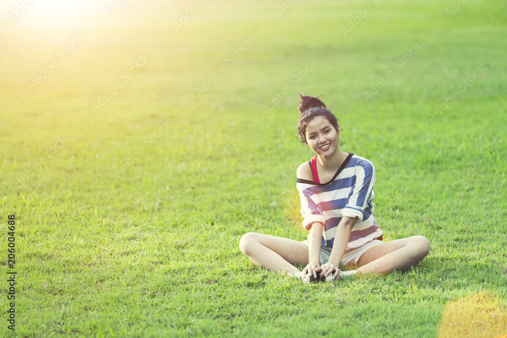 Happy young woman relax and smiling on green grass with sunrise in morning. Happy life lifestyle. Good healthy concept. Happy young woman relax and smiling on green grass with sunrise in morning. Happy life lifestyle. Good healthy concept.
