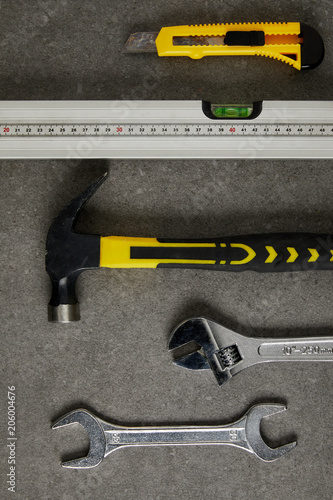 spirit level, hammer, adjustable wrench ans spanner on gray surface