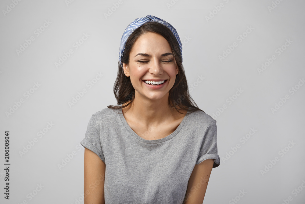 Beautiful girl in her twenties enjoying leisure time, laughing with eyes closed. Picture of cute charming young lady dressed casually not able to resist laughter, feeling relaxed and carefree Beautiful girl in her twenties enjoying leisure time, laughing with eyes closed. Picture of cute charming young lady dressed casually not able to resist laughter, feeling relaxed and carefree