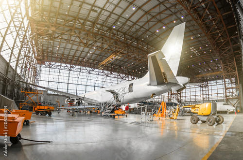 Large passenger aircraft on service in an aviation hangar rear view of the tail, on the auxiliary power unit. Mechanization of the tail is dismantled.