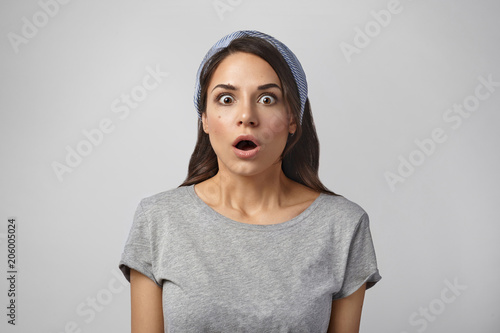 Beautiful shocked girl being at panic because she forgot to switch off iron before leaving home. Picture of astonished amazed young female opening mouth widely, staring at camera in amazement