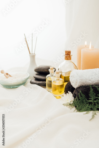 close up view of arrangement of spa treatment accessories with candles and pebbles on white background