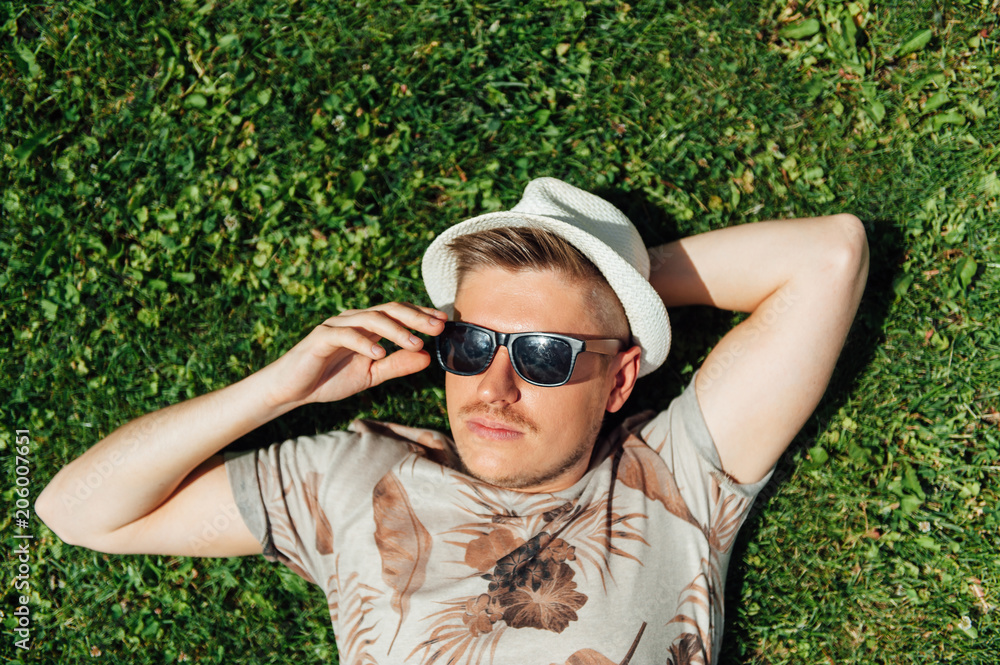 stylish hipster guy lying on the grass stylish hipster guy lying on the grass