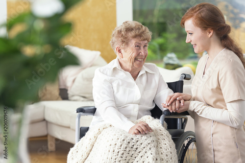 Smiling grandmother on the wheelchair and friendly nurse
