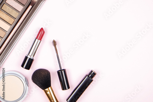 Feminine desktop top with bunch of cosmetics: eye shadow palette, brow mascara, brush, blusher powder w/ mirror. Woman's table top & her beauty accessories. Background, top view, flat lay, copy space