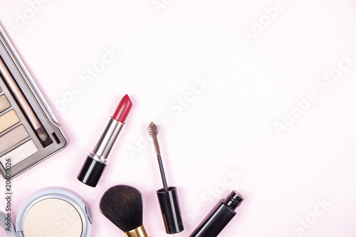 Feminine desktop top with bunch of cosmetics: eye shadow palette, brow mascara, brush, blusher powder w/ mirror. Woman's table top & her beauty accessories. Background, top view, flat lay, copy space