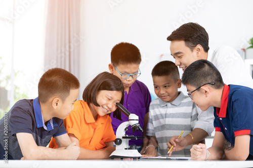 Asian girl and boy examining preparation under the microscope