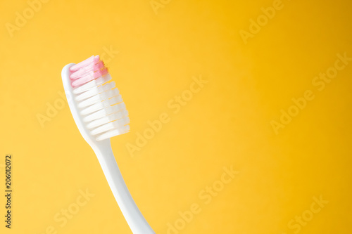 Close-up white plastic toothbrush on yellow background