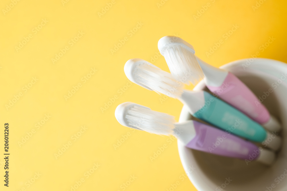 Close-up three white plastic toothbrushes in white mug on yellow background, Selected focus Close-up three white plastic toothbrushes in white mug on yellow background, Selected focus