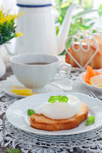 Bright breakfast with a cup of tea, white bread toast with poached egg and marmalade, selective focus