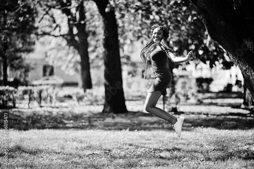 Cute and slim african american girl in red dress with dreadlocks jump outdoor in spring park. Stylish black model.