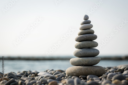 a pyramid of stones on a pebble beach against the sea and sky.