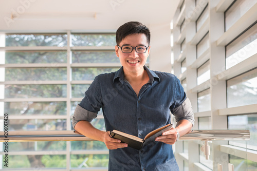 Young handsome cute men student smiles and reads a book in university