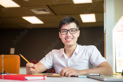 Young handsome cute Asian men student smiles and do homeworks in university