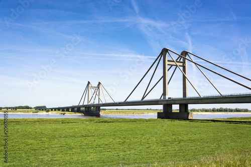 Dutch landscape with bridge over the river Waal in the Netherlands, with blue sky and green meadows