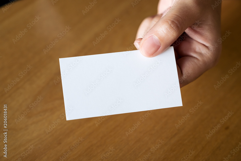 Closeup image of hands holding and giving an empty business card to someone on table in office Closeup image of hands holding and giving an empty business card to someone on table in office