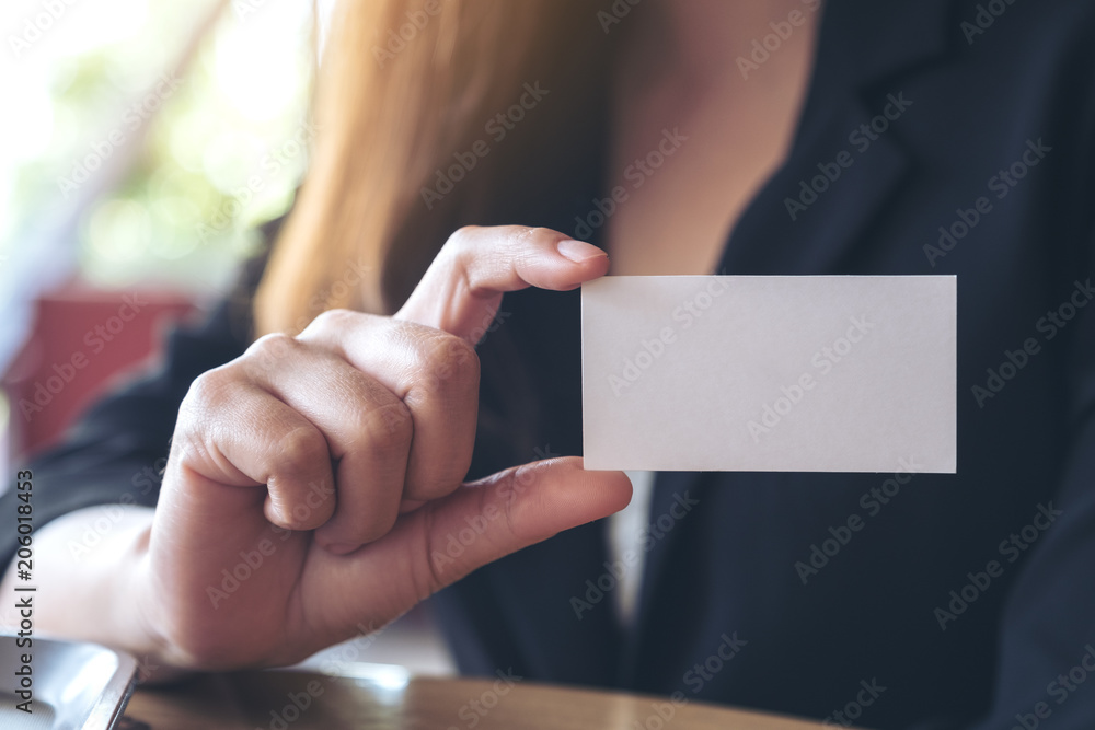 A businesswoman holding and showing an empty business card - obrazy, fototapety, plakaty 