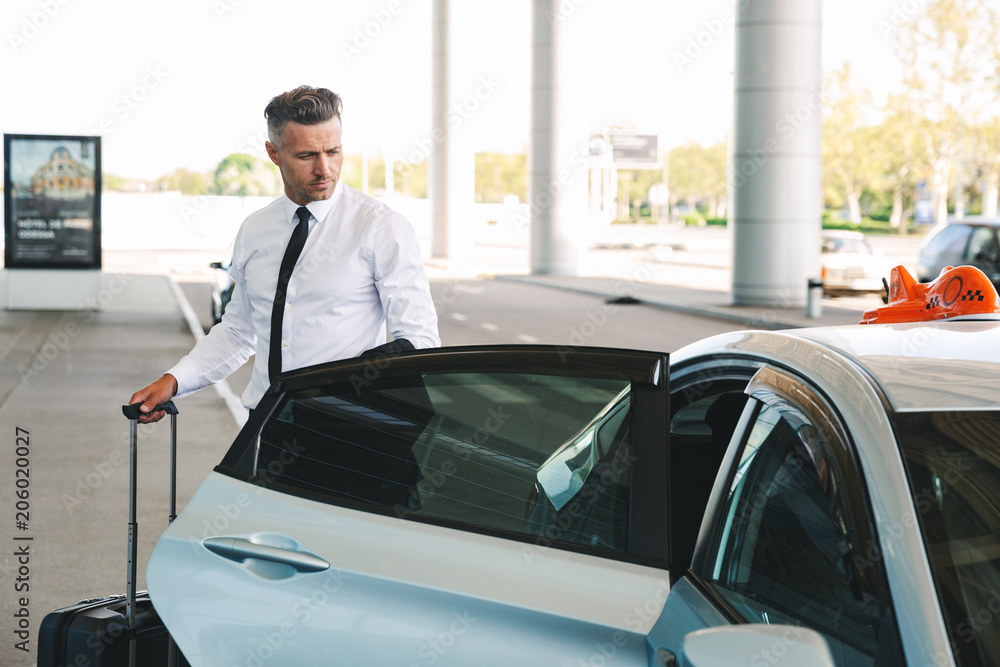 Fototapeta premium Handsome mature businessman getting in taxi