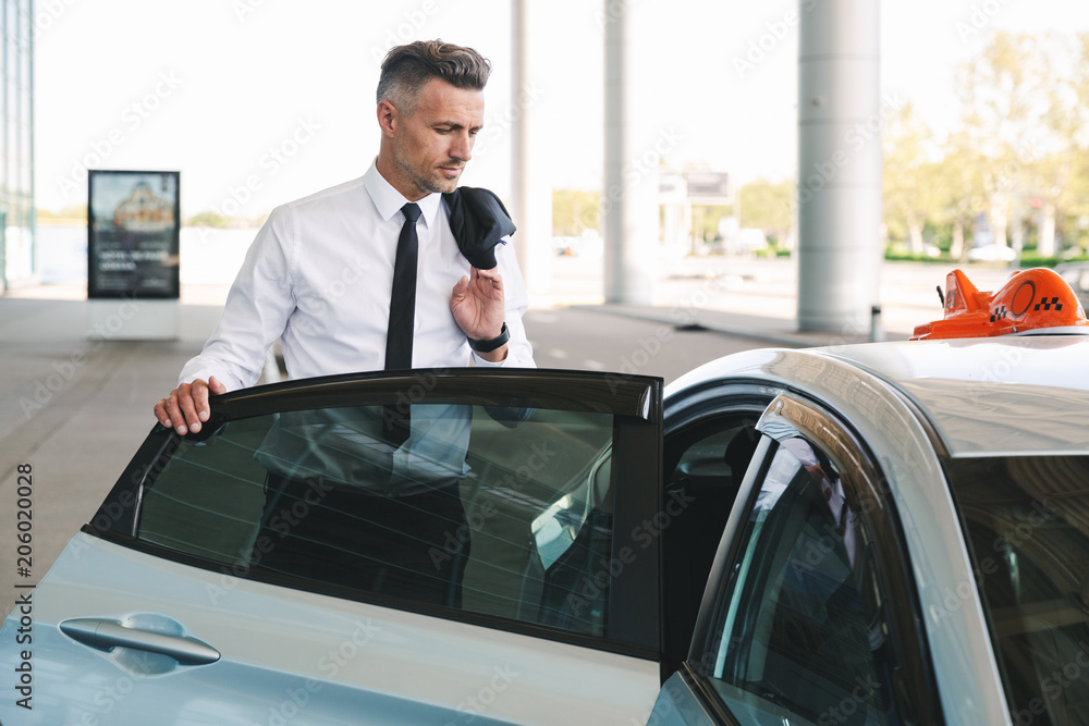 Successful mature businessman getting in taxi Successful mature businessman getting in taxi