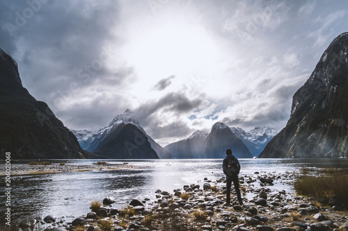 A backpacker man with jacket and beanie enjoying with the stunning scenery of the ford land at Milford Sound, New Zealand