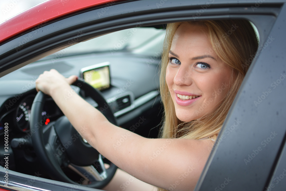 Young, pretty blonde girl driving red car