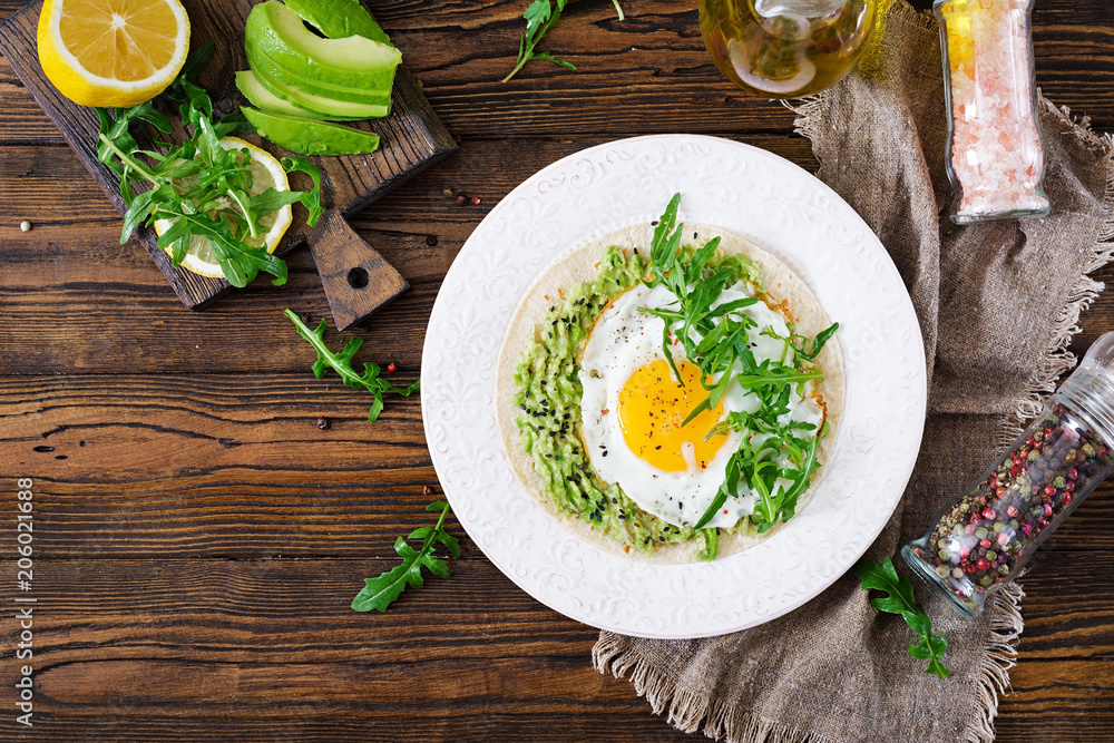 Tacos with guacamole, fried egg and arugula. Healthy food. Useful breakfast. Flat lay. Top view Tacos with guacamole, fried egg and arugula. Healthy food. Useful breakfast. Flat lay. Top view