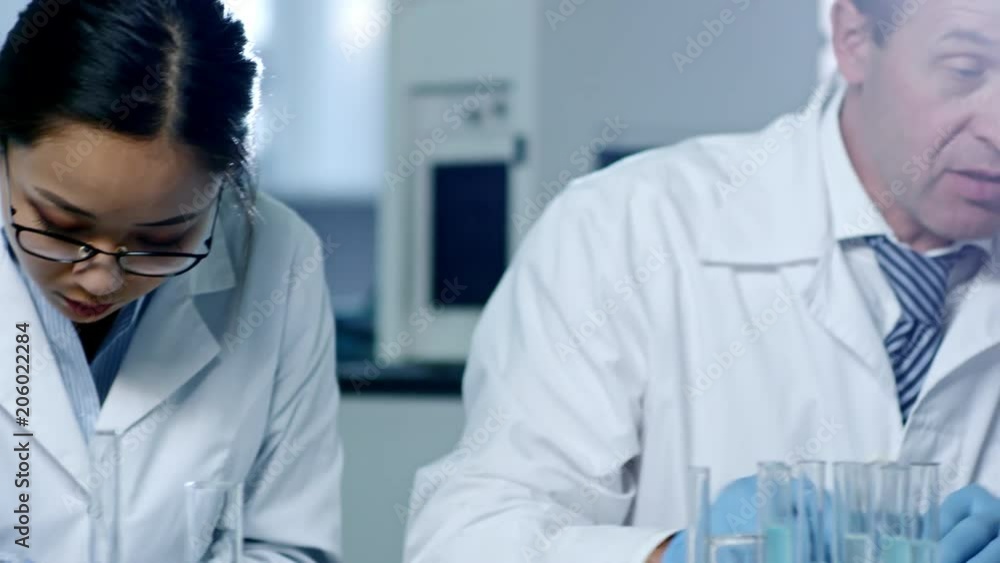 Group of three scientists studying plant specimens in laboratory using microscope, test tubes and Florence flasks Group of three scientists studying plant specimens in laboratory using microscope, test tubes and Florence flasks