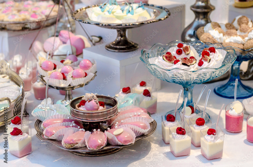 Naklejka premium Candy Bar. Sweet round candy in pink and white glaze with raspberries on tartlets. Happy luxury birthday and wedding concept. Party sweets.