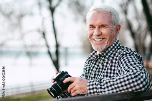 Improve your skills. Merry mature man utilizing camera and grinning to camera © zinkevych