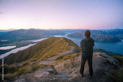 A young Asian man enjoying looking at the stunning scenery on the high mountain before sunset. © Klanarong Chitmung