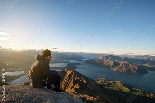 A young Asian man enjoying looking at the stunning scenery on the high mountain before sunset.