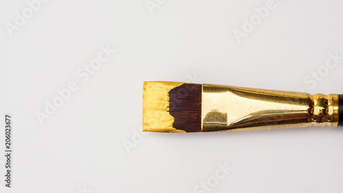Paintbrush and gold colored poster on a white background.