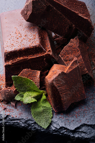 Dark chocolate stack, and powder.Closeup.With leaf of mint hocolate.Sweet delicious.On dark background photo