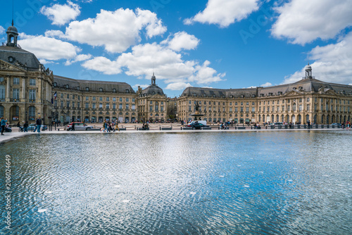 Bordeaux, France, 10 may 2018 : Tourists visiting the Place de la Bourse seen from the boulevard with in front the mirror fountain: 'Mirroir d'eau'