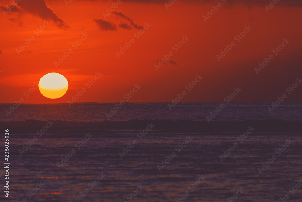 Sunrise over ocean horizon photographed with big telephoto lens.