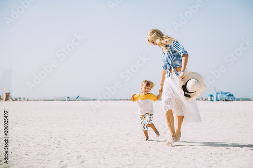 Photography Young mother and happy little son at sandy beach in Dubai, UAE