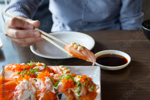 People use chopsticks to pick up sushi.