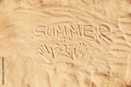 Inscription word summer and hand prints on sand.