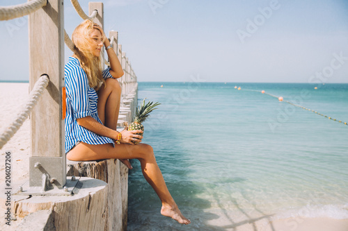 Photography Beautiful young blonde woman with pineapple posing at pier