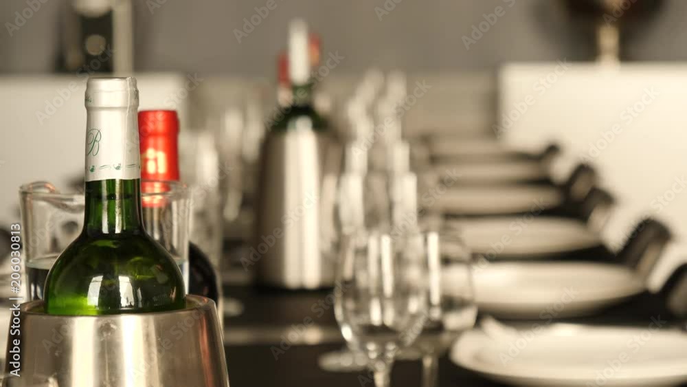 A woman in classy dress places wine glasses on nicely set, long table. A woman in classy dress places wine glasses on nicely set, long table.
