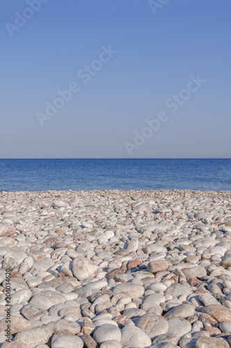 Pebble stony beach and blue wave sea with clean sky