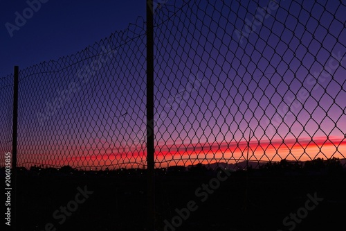 Silhouette of view near town on sunset trough a fence photo