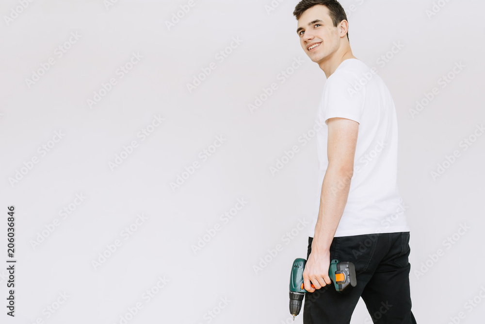 A young guy holding a screwdriver, a drill with his hand. Іsolated white background