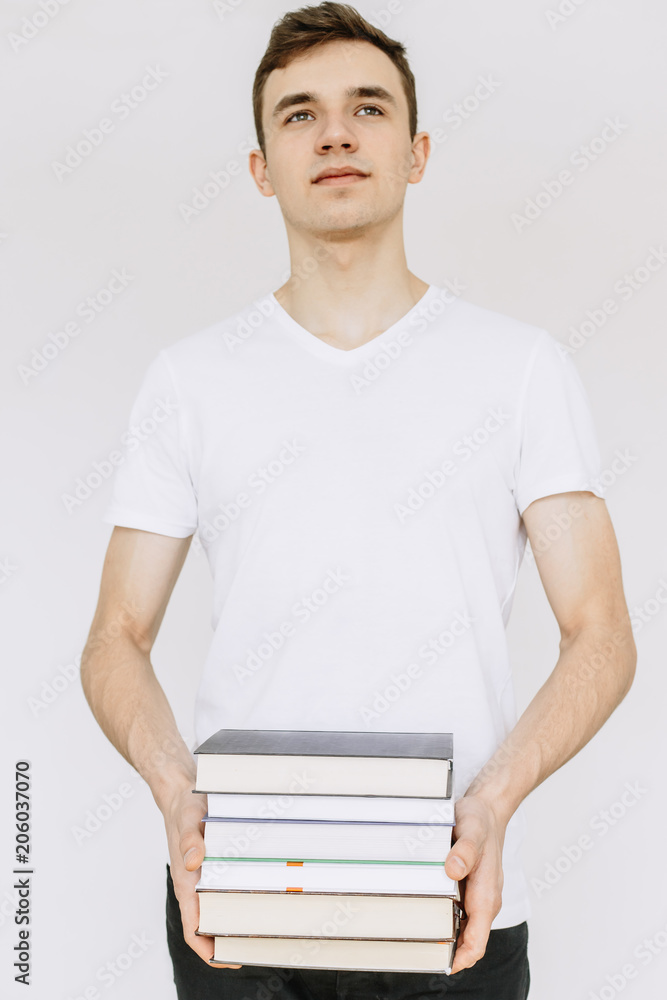 A young guy looks straight and holds books in his hands. Іsolated white background A young guy looks straight and holds books in his hands. Іsolated white background